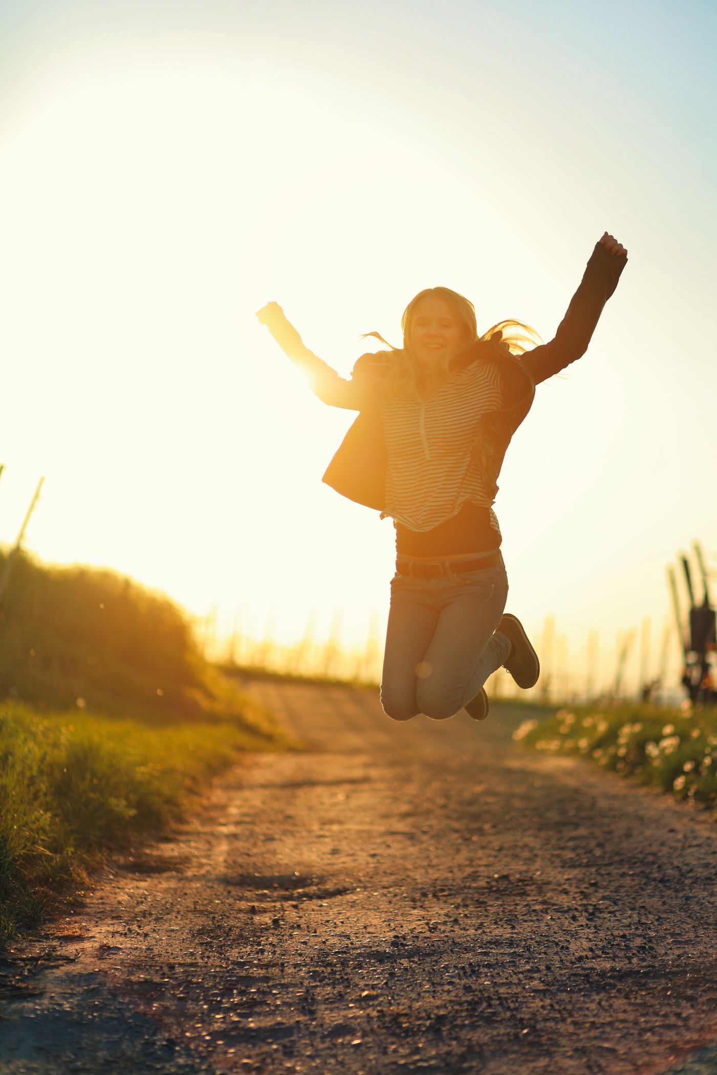 A woman raising her arms joyfully in warm golden light